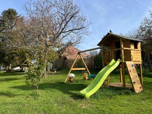 a playground with a slide and a play house at Öregfenyő Tornácosház in Bakonykoppány