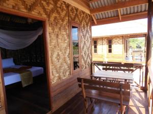 a cabin with a porch with a bed and a bench at Ban Ban Bangalow in Ko Jum