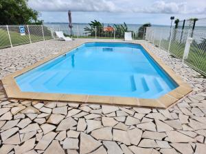 a swimming pool with blue water on a stone patio at Nemo sur mer in Petit-Bourg