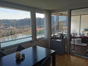 a living room with a table and large windows at Beautiful view on the river Aare in Hinterkappelen