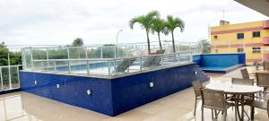 a balcony with a pool and tables and chairs at Apto Vista do Pôr do Sol SUN7 in Ilhéus