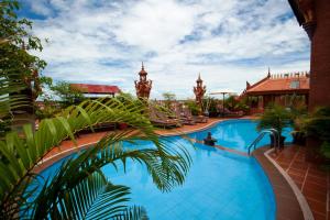 a pool at a resort with a palm tree in the foreground at Okay Guesthouse Siem Reap in Siem Reap