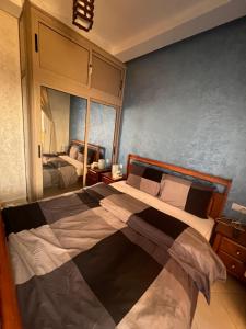 a bedroom with a large bed and a mirror at Appartement Dari proche du centre ville in Agadir