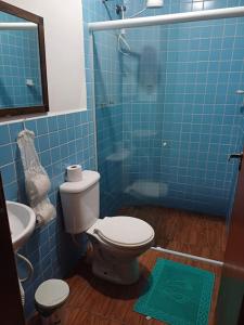 a blue tiled bathroom with a toilet and a sink at Seu descanso merecido está aqui in São Sebastião