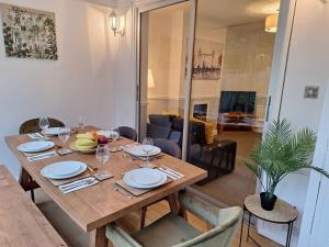 a wooden table with plates and wine glasses on it at Cosy & Comfortable 3 Bed House, Office & Driveway in London
