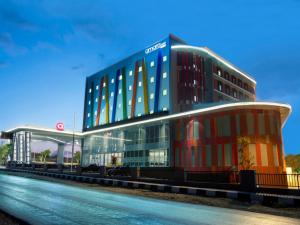 a large building with glass windows next to a street at Amaris Hotel Kupang in Kupang