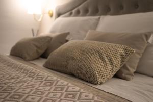 a bed with white pillows and a white headboard at Lume Guest House in Catania