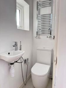 a white bathroom with a toilet and a sink at Cosy 4-Bedroom Entire Home - Sleeps 7, Oxford in Oxford