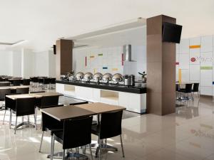 a restaurant with tables and a kitchen with a counter at Amaris Hotel Kupang in Kupang