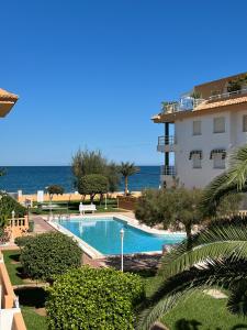 a swimming pool next to a building and the ocean at Apartamento frente al mar, Talima in Denia