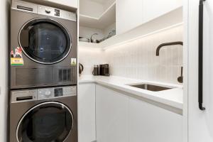 a kitchen with a washer and dryer next to a sink at Luxury Central Villa with Spa Pool Prime Location in Auckland