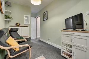a living room with two chairs and a flat screen tv at The Old Bike Cabin Flat 1 in Heapey