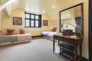 a bedroom with two beds and a mirror and a desk at Riber Hall in Matlock Bank +15 photos