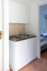 a kitchen with white cabinets and a sink and a bed at Beach Hotel in Drasnice