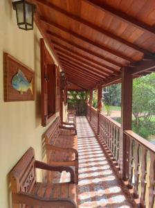 a porch with wooden benches on a house at Casa à Beira da Lagoa,Tiradentes in Tiradentes