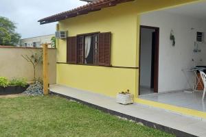 a yellow and white house with a door and a yard at Simplesmente aconchegante in Itapoa