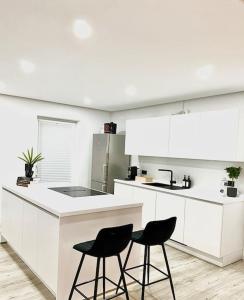a white kitchen with two black chairs in it at Highlife Apartment Bad Kreuznach ONE in Bad Kreuznach
