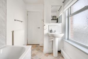 a white bathroom with a tub and a sink and a window at The Old Bike Shop Flat 2 in Heapey +24 photos