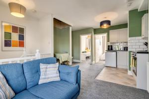 a living room with a blue couch and a kitchen at The Old Bike Shop Flat 2 in Heapey