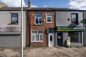 a brick building with a white door on a street at The Old Bike Shop Flat 2 in Heapey