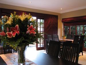 a vase of flowers on a table in a dining room at Njala Guest House in Middelburg