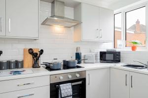 a kitchen with white cabinets and a stove top oven at Enchanting 4 spacious bedrooms in Birmingham
