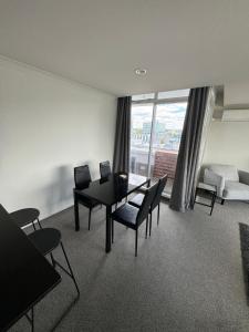 a living room with a table and chairs and a couch at Corporate Accommodation - Modern CBD Apartment in Hamilton
