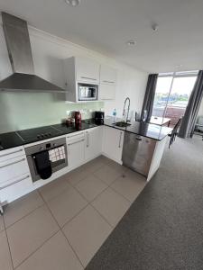 a kitchen with white cabinets and a stove top oven at Corporate Accommodation - Modern CBD Apartment in Hamilton +1 photo
