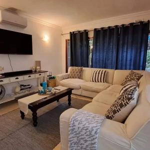 ジンクワジ・ビーチにあるSea Esta Coastal Beach Houseの白いソファとテレビのあるリビングルーム