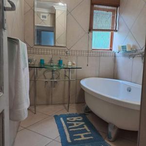 ジンクワジ・ビーチにあるSea Esta Coastal Beach Houseの浴槽、洗面台、鏡のあるバスルーム