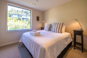 a bedroom with a large white bed with a window at The Sands Penthouse 11 - Stay Waiheke in Waiheke Island