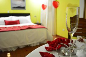 a bedroom with a bed and a table with a wine glass at Ecohotel La Casona Pereira in Pereira