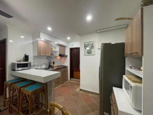 a kitchen with a counter with stools and a refrigerator at Apartamento soberana del mar bello horizonte in Playa Bello Horizonte