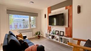 a living room with a blue couch and a tv at Aiila House in Esquel