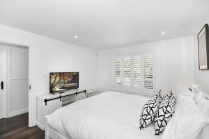 a white bedroom with a large bed and a window at Margaret's Hamptons Beach House in Hawks Nest