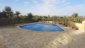a large swimming pool in the middle of a sandy yard at Tunis Tone Ecolodge & Campsite in Fayoum Center +7 photos