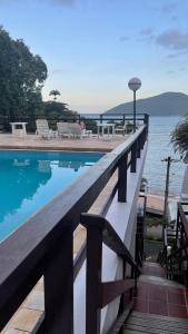 ウバトゥバにあるLoft maravilhoso, com vista sensacional do marの水辺の景色を望むスイミングプール(椅子付)