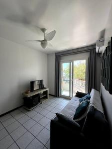 a living room with a couch and a ceiling fan at Ap no centrinho de Canasvieiras ,2 quadras mar in Florianópolis