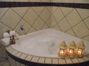 a bath tub with two candles in a bathroom at Njala Guest House in Middelburg