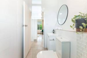 a white bathroom with a toilet and a mirror at 'Tres Botanica' Nightcliff Escape for Groups, Three Adjacent Apartments in Nightcliff +33 photos