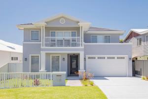 a house with a white fence in a yard at Shoreline Luxe - Refined Beachside Elegance with Spa in Caves Beach