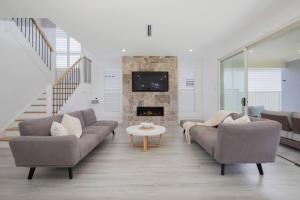a living room with two couches and a fireplace at Shoreline Luxe - Refined Beachside Elegance with Spa in Caves Beach