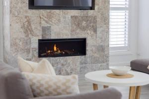 a living room with a fireplace and a couch at Shoreline Luxe - Refined Beachside Elegance with Spa in Caves Beach