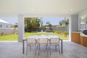 a dining room with a table and chairs at Shoreline Luxe - Refined Beachside Elegance with Spa in Caves Beach