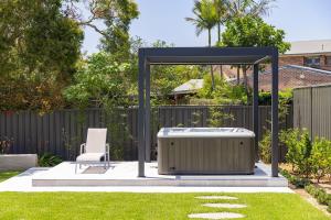 a gazebo with a hot tub in a yard at Shoreline Luxe - Refined Beachside Elegance with Spa in Caves Beach