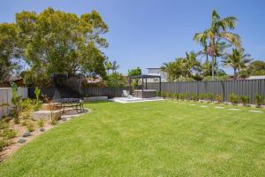 a garden with a picnic table and a fence at Shoreline Luxe - Refined Beachside Elegance with Spa in Caves Beach