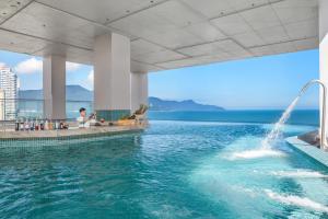 a swimming pool with a fountain in the water at Awaken Da Nang Hotel in Danang