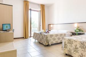 um quarto de hotel com duas camas e uma televisão em Hotel Rondine em Marinella di Sarzana