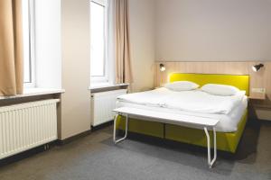 um quarto com uma cama com uma cabeceira amarela em Corner Hotel em Vilnius