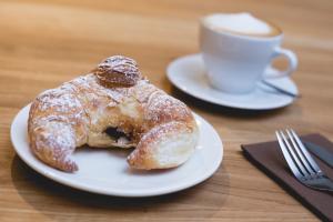 two donuts on a plate next to a cup of coffee at Corner Hotel in Vilnius